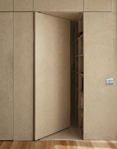 an open door in the middle of a room with wood flooring and beige walls