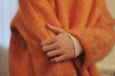 a person in an orange coat with their hand on the wrist