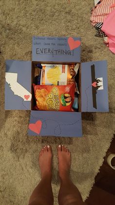 someone's feet are standing in front of an open box that has food inside