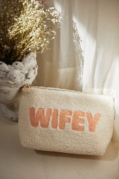 a white purse sitting on top of a table next to a vase filled with flowers