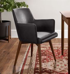 a black leather chair sitting on top of a wooden table next to a potted plant