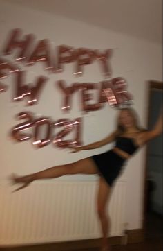 a woman is jumping in the air with her legs spread out and balloons that say happy new year