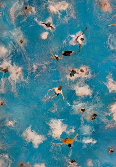 several people swimming in a pool with blue water and white clouds on the bottom half