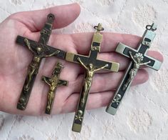 three antique crucifixs in the palm of a person's hand