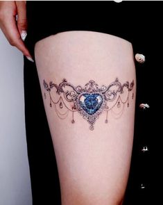 a woman's thigh with a blue heart tattoo on her left side ribcage