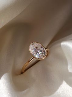 a close up view of a diamond ring on a white cloth with the light shining through it