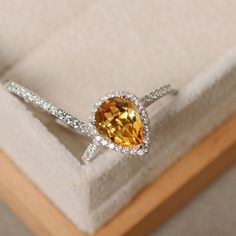 This halo ring features a 7*9mm pear cut natural citrine and sterling silver finished with rhodium. Customization is available. It is made by hand, and it will take about 7 days to finish the ring after your payment is completed. Main stone: genuine citrine Citrine weight: Approx 1.90 ct Metal type: sterling silver finished with rhodium Accent stone: cz Customization is available, I also can make it with 14k solid gold (white or yellow or rose) and diamond accent stone, just feel free to contact White Gold Citrine Jewelry With Halo Setting, Elegant Yellow Pear-shaped Diamond Ring, Silver Pear-shaped Ring With Halo Setting, Silver Pear-shaped Rings For Promise, Pear-shaped Silver Cubic Zirconia Wedding Ring, Elegant Topaz Teardrop Rings, Yellow Topaz Sterling Silver Wedding Ring, Yellow Sterling Silver Halo Setting Jewelry, Yellow Sterling Silver Ring With Halo Setting