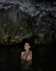 a woman is in the water near a cave