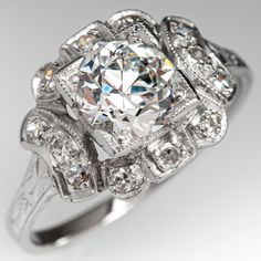 This gorgeous circa 1930s engagement ring features a pierced design and is bordered with milgrain edging. The ring is centered with one (1) round transitional brilliant cut diamond weighing 0.90 carat and set into a four-prong head. The center stone is bordered with twelve (12), bead set, round single cut diamonds. Engraved details accent the top half of the shank. The ring measures 10.8mm at the top, rises 5.4mm above the finger, tapering to 1.5mm wide and 0.9mm thick at the base of the shank. Wedding Diamond Ring With Milgrain, Heirloom Milgrain Round Cut Wedding Rings, Round Cut Diamond Ring With Milgrain Detail, Classic Round Diamond Ring With Milgrain Detailing, Heirloom Style Diamond Ring With Milgrain And Round Cut, Heirloom Style Milgrain Diamond Ring With Round Cut, Heirloom Diamond Ring With Milgrain, Round Cut, Heirloom Milgrain Round Cut Diamond Ring, Heirloom Style Round Cut Diamond Ring With Milgrain