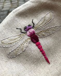 a close up of a dragonfly embroidered onto a piece of cloth with beads on it