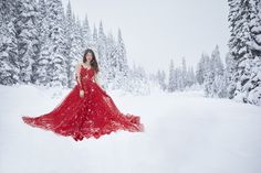 a woman in a red dress standing in the snow