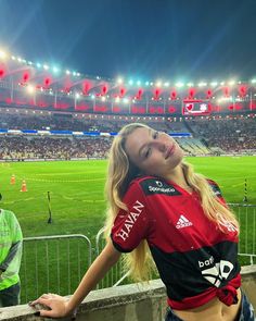 a beautiful young blonde woman standing next to a soccer field