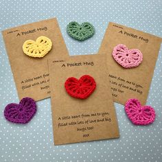 four crocheted hearts are displayed on brown paper