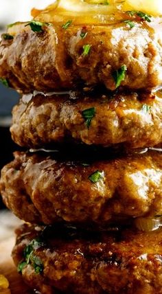 three hamburger patties stacked on top of each other with cheese and herbs in the middle