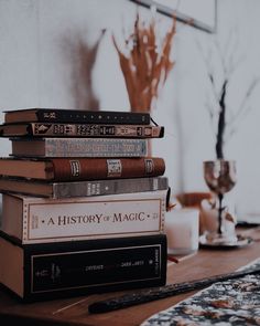 a stack of books sitting on top of a wooden table next to a vase filled with flowers