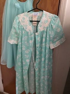 New old stock, robe housecoat with Marshall's tag, Size Small.  This in a floral turquoise and white quilted polyester cotton blend,  with a pocket on the right side. Short sleeves.  Stud closures all the way down the front, small ribbons to tie a bow at the neck.  Length: 40 inches Shoulder to shoulder: 32 inches Bust about 34 inches. Waist 34 inches Arm opening 14 inches. Free shipping on all nightwear, will combine shipping. Heidi Gibson, Girls Camp, Nightgowns For Women, Womens Robes, Nightgowns, 1980s Vintage, Right Side, Nightwear, Night Gown