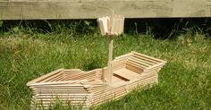 a wooden boat sitting on top of a lush green field