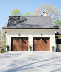 two garages with brown doors in front of a white house