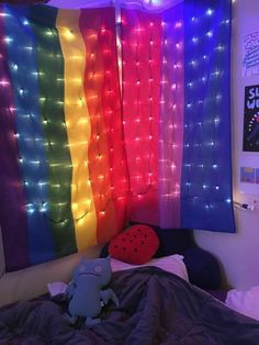 a bed with a rainbow colored curtain hanging over it