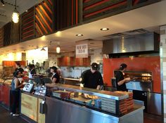 people are standing in line at the counter of a fast food restaurant that is open for business