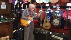 an older man is playing his guitar in the store