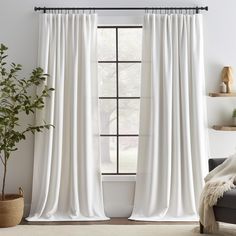 a white curtain hanging in front of a window with a potted plant next to it