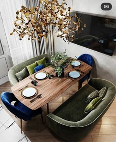 a dining room table with blue chairs and plates on it, next to a green couch