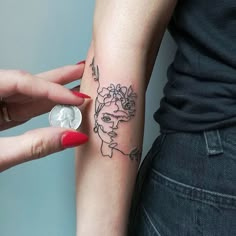 a woman's arm with a tattoo on it and a coin in front of her