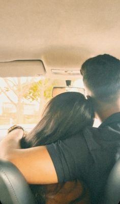 a man and woman are sitting in the back seat of a car, embracing each other