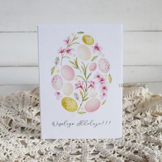 a card with an image of eggs and flowers on it, sitting on a lace doily