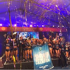 a group of cheerleaders standing on stage with confetti in the air