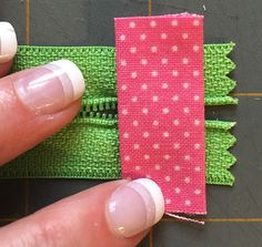 someone is stitching the side of a pink and green piece of fabric with white stitches