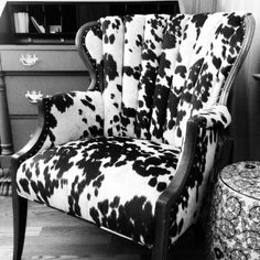 a cow print chair sitting in front of a green dresser