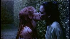 two people kissing each other in front of bushes and trees, one woman with red hair has her face close to the man's mouth