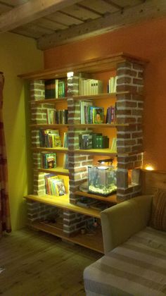 a living room filled with furniture and bookshelves next to a wall mounted fish tank