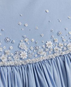 a blue dress with white flowers and pearls on the bouddy skirt is shown