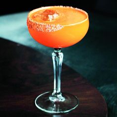 an orange cocktail sitting on top of a wooden table