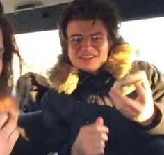 two people sitting in the back seat of a car, one holding a stuffed animal