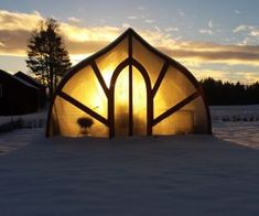 the sun is setting behind a small building in the middle of snow covered yard area