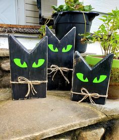 three black boxes with green eyes are sitting on the steps in front of a house