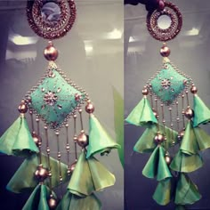 two pictures of green and gold earrings hanging from hooks with chains attached to the ends