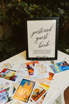 a sign that says postcard guest book sitting on top of a table filled with cards