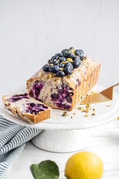 a loaf of lemon blueberry bread on a white plate with a slice cut out