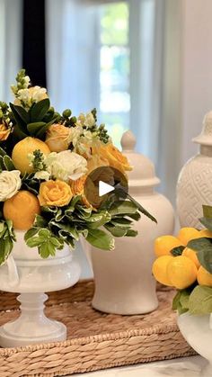 a vase filled with yellow flowers sitting on top of a counter next to other vases