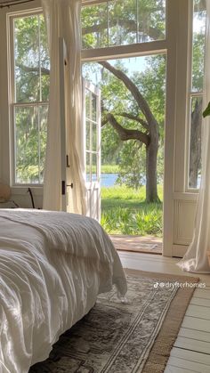 a large bed sitting in front of a window next to a white rug on top of a wooden floor