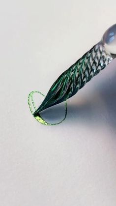 a close up of a pen on a white surface with a green cord attached to it