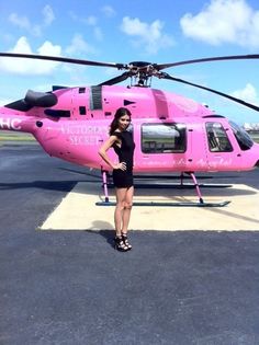 a woman standing in front of a pink helicopter