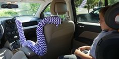 a young boy sitting in the back seat of a car wearing a blue and white chevron ribbon