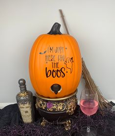 a halloween pumpkin with writing on it next to a bottle of booze and a glass of wine