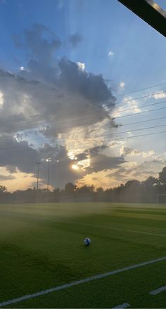 the sun is setting over a soccer field